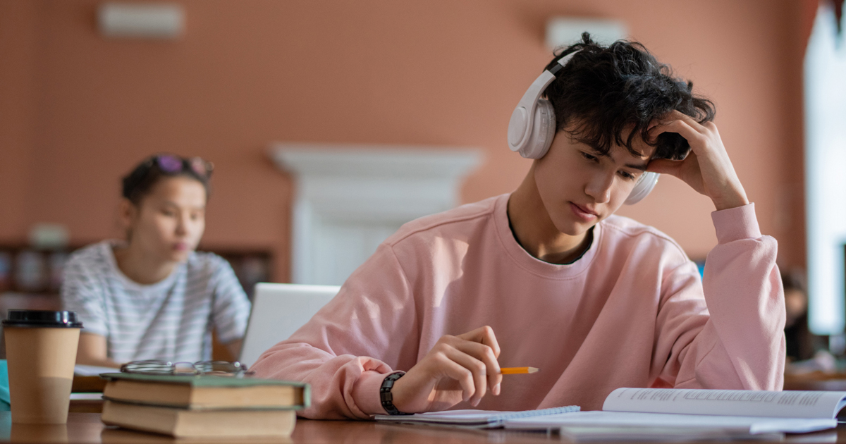 Teenage boy with headphones on, sitting in class