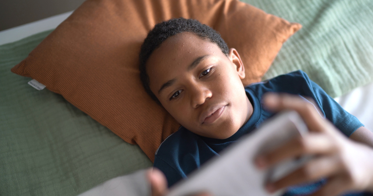 Boy on pillow with phone.