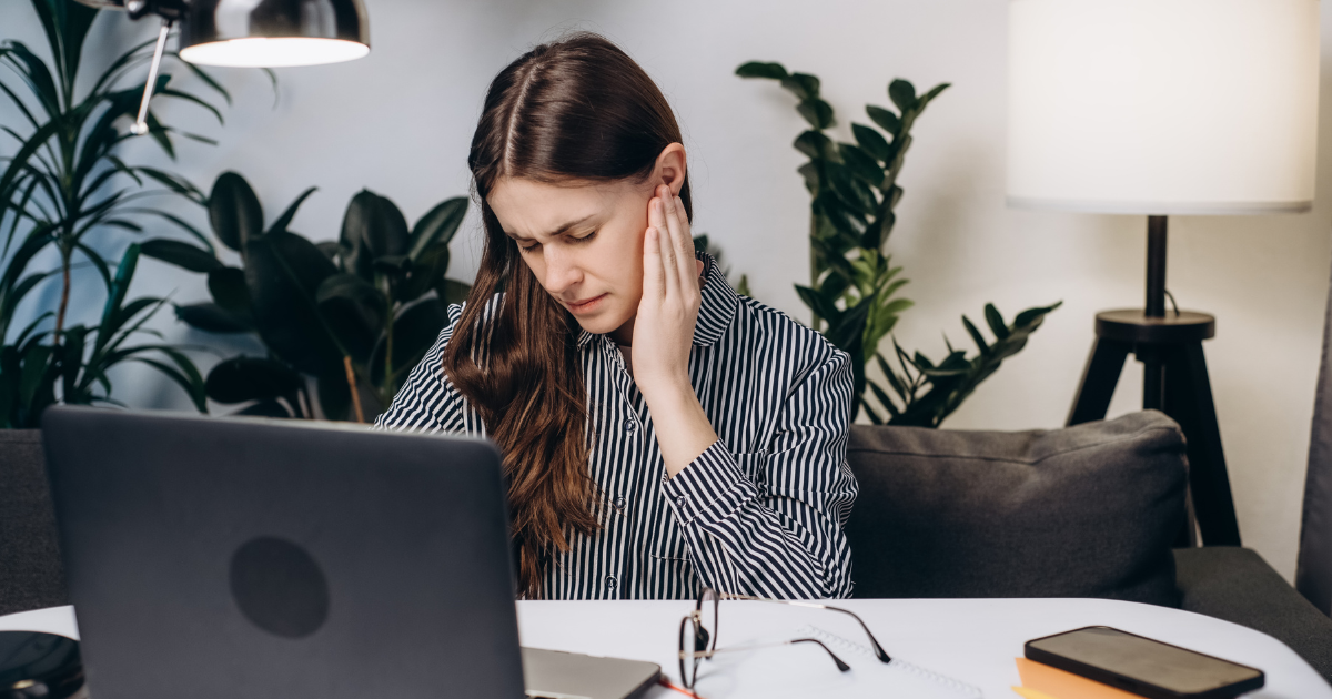 A picture of a woman holding her ear in pain