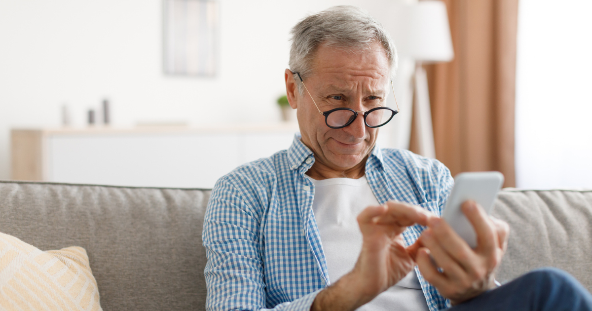 Picture of a man with glasses looking at his cellphone