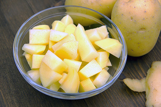 Glass bowl filled with cubed potatoes.