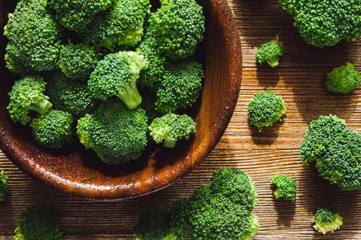 A wooden bowl filled with broccoli. 