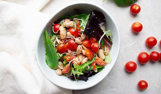 Bruschetta salad with white beans in a white bowl. 