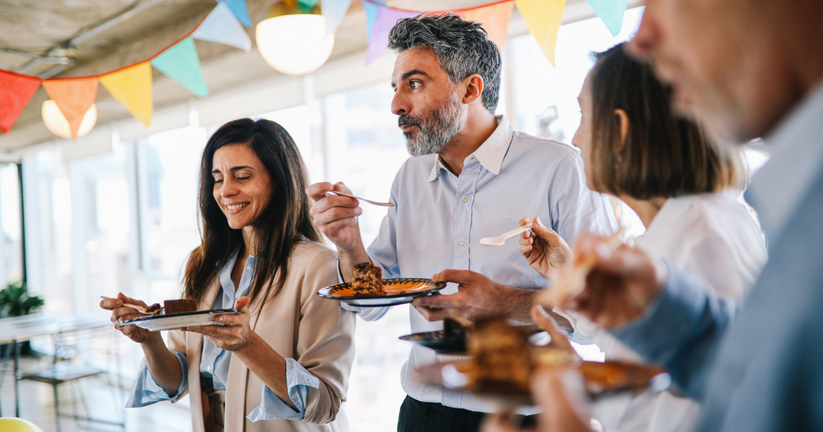 Man eating cake with his colleagues at a party