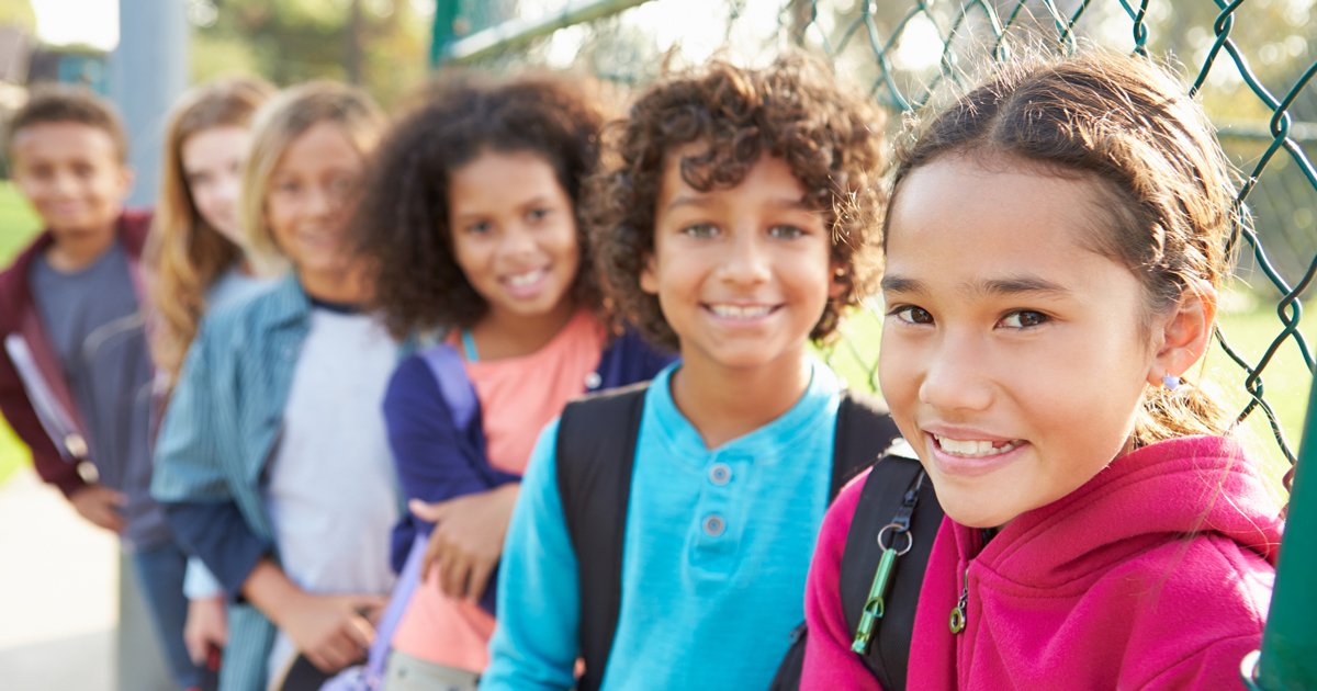 Line of young girls standing against a chain link fence