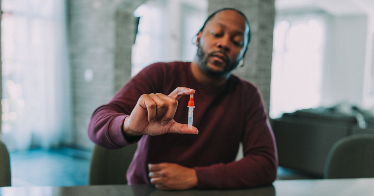 Man holding up a vial from an at-home COVID test