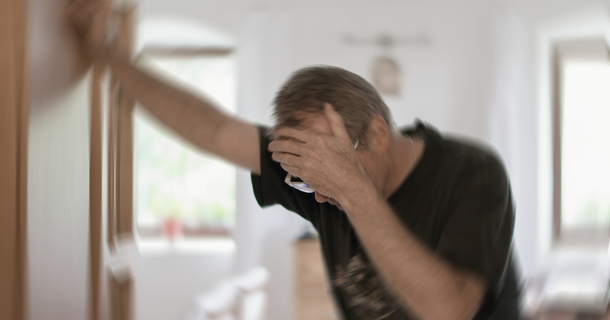 Man dizzy leaning on a doorway