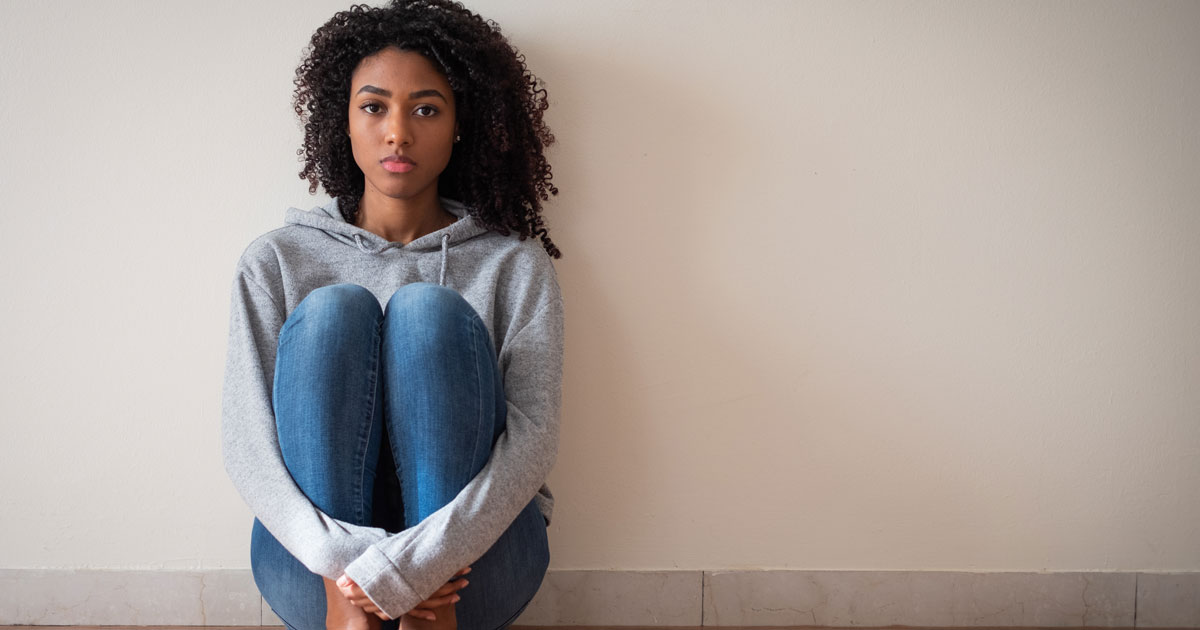 A woman sitting near a wall