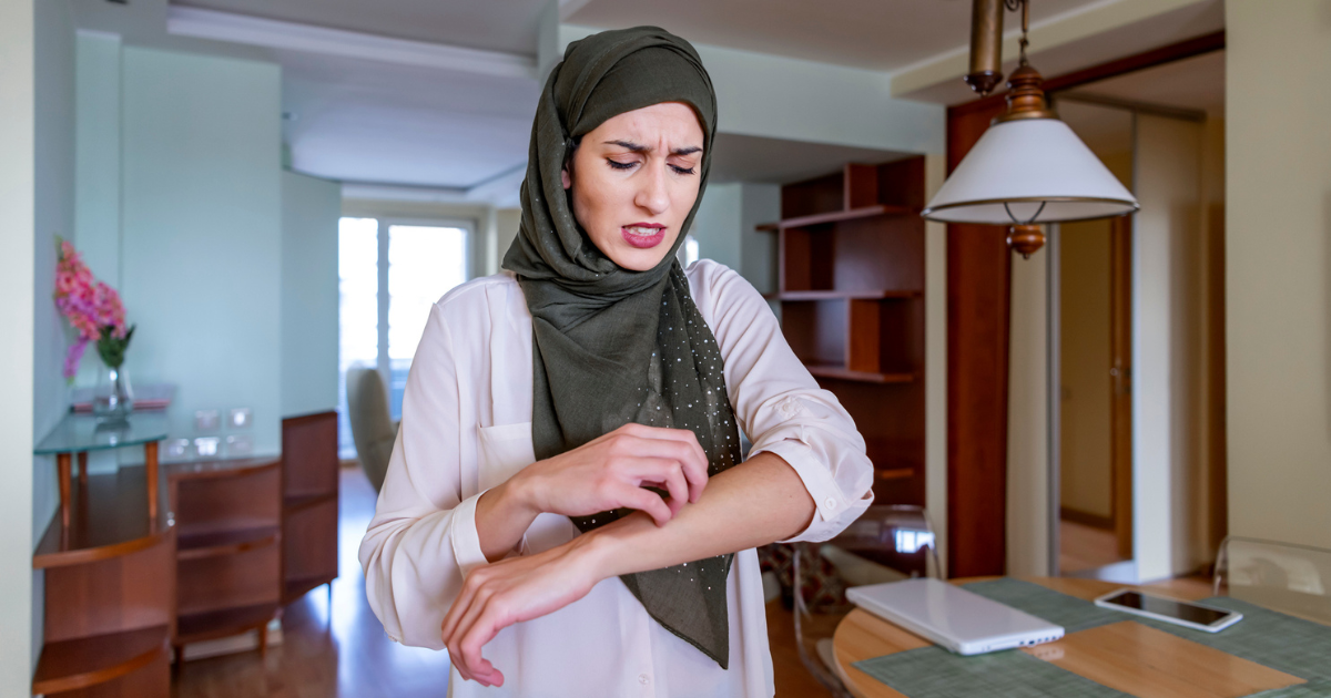 Woman wearing a hijab scratching her forearm