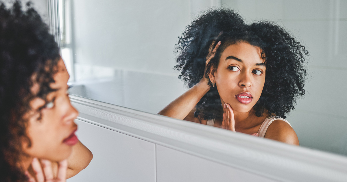 Woman looking at her skin in mirror