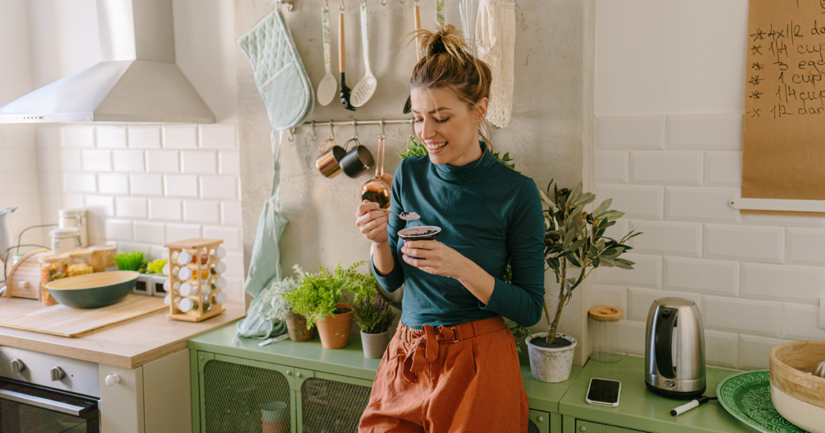 Woman standing in her kitchen eating