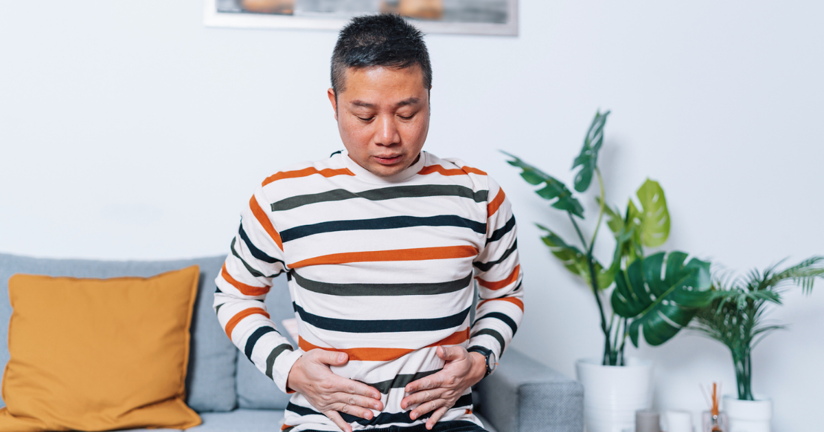 Man sitting on the couch, holding his stomach