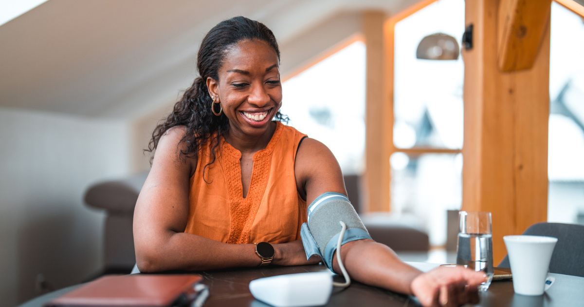 Woman sitting at a table checking her blood pressure