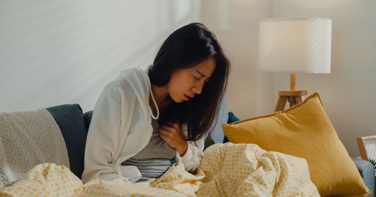 Woman sitting on the couch coughing