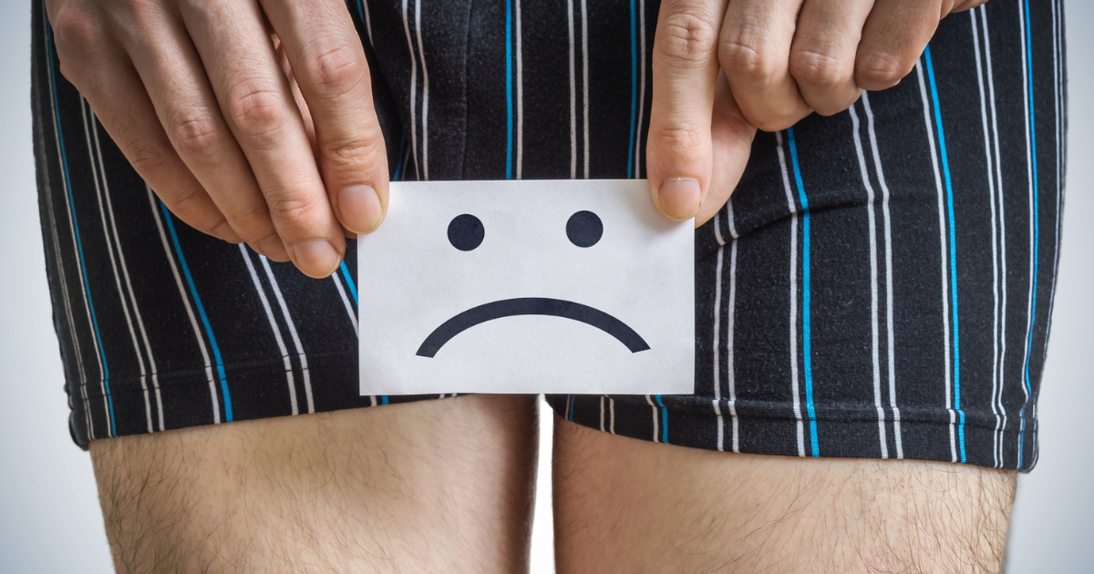 Sad face drawn on a piece of paper, held in front of a man's waist