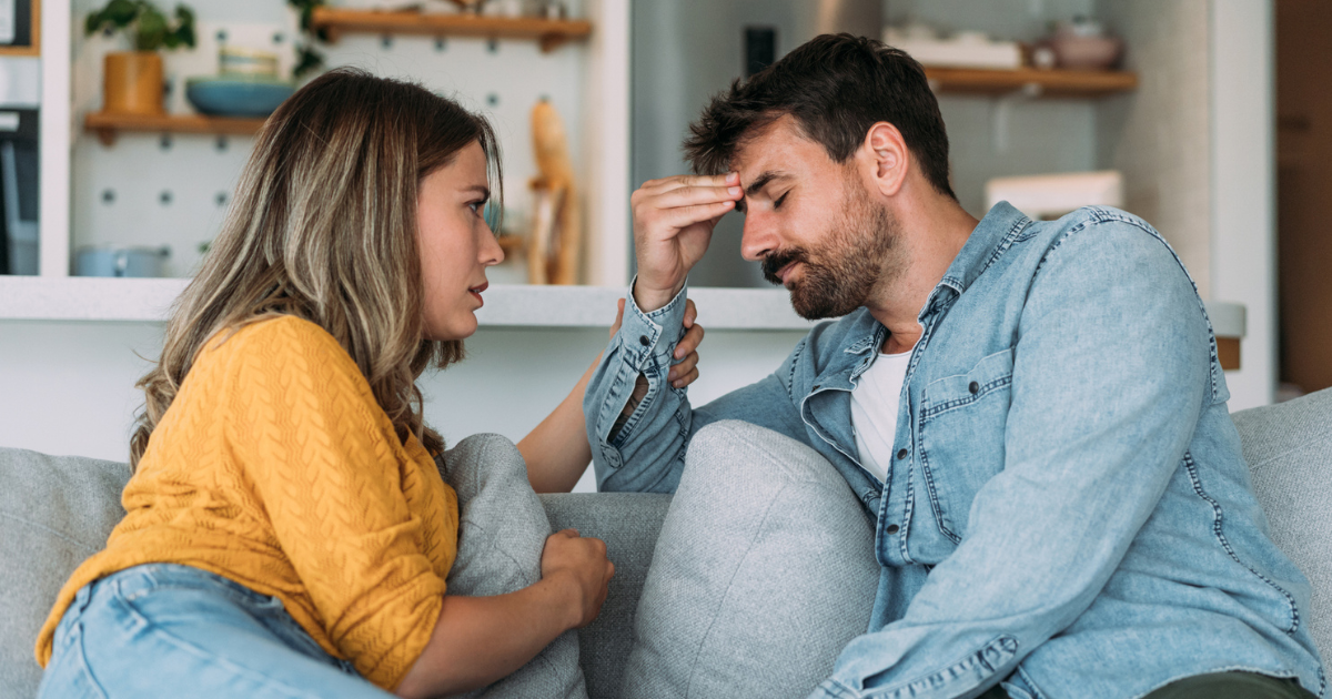 Confused man sitting on the couch with a concerned woman