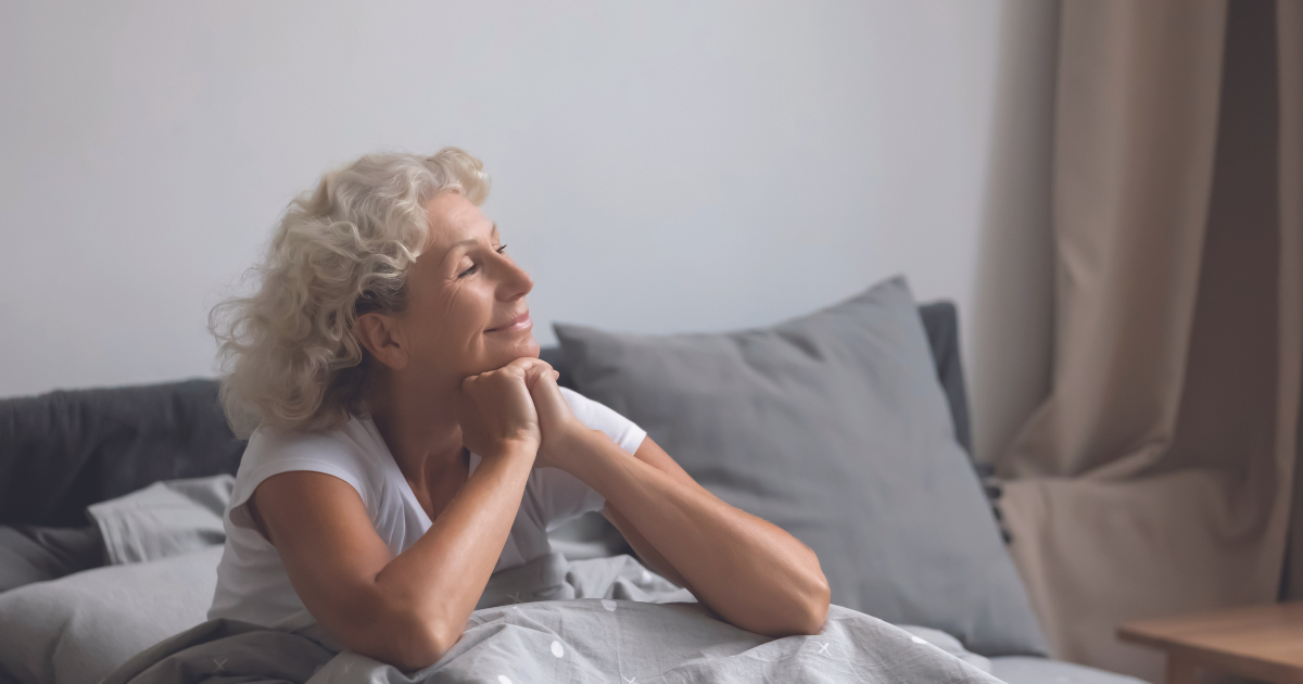 Woman sitting up smiling in bed