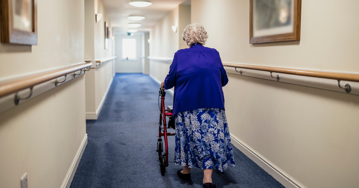 Senior woman walking down a hallway with a walker