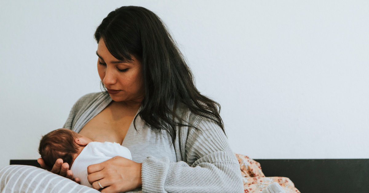 Woman breastfeeding sitting in her bed