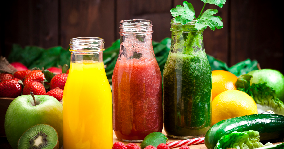 Three juice bottles surrounded by fruit