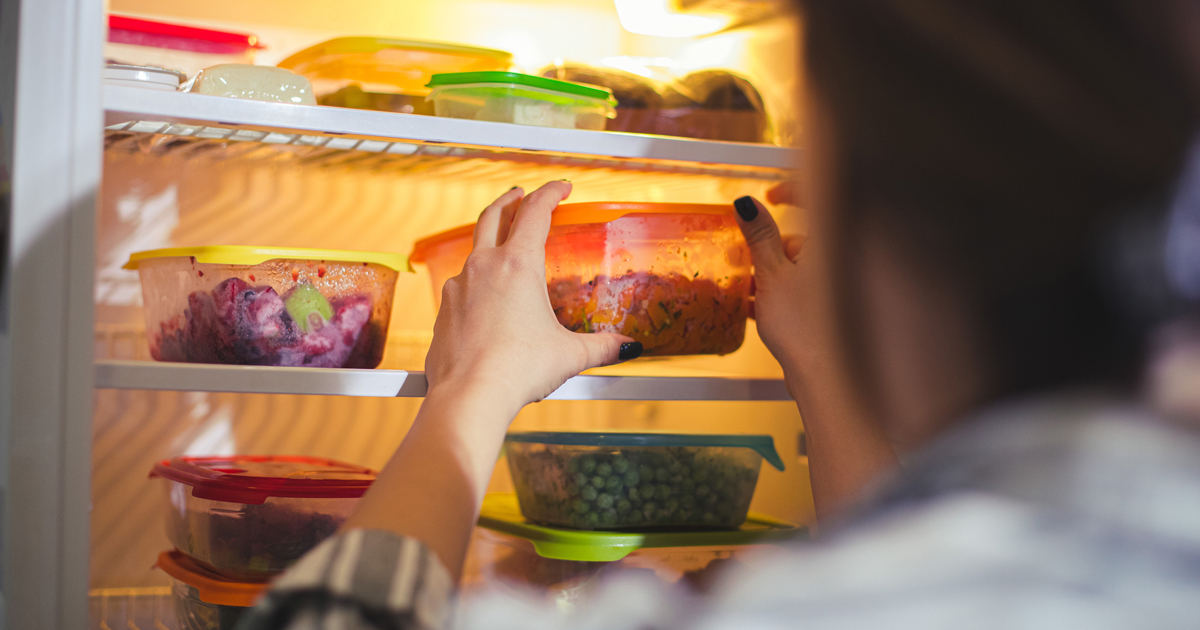 Woman reaching for Tupperware containers in her fridge