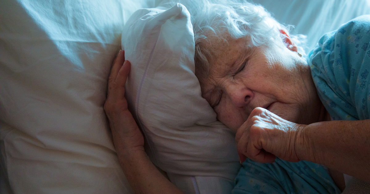 Older woman coughing in bed