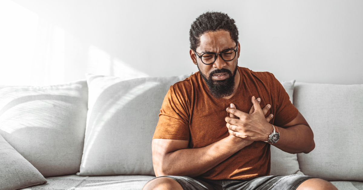 Man sitting on the couch holding his chest