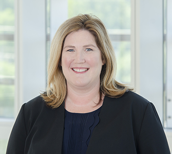 Jayme Dowdall, MD standing in front of a bright background smiling brightly