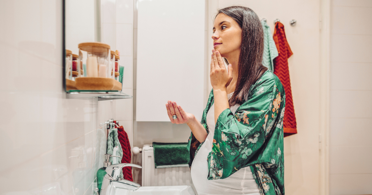 Pregnant woman applying a skin care product in her bathroom