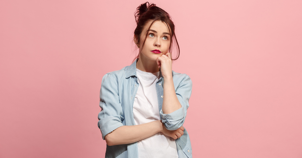 Young woman holding her chin against a pink background