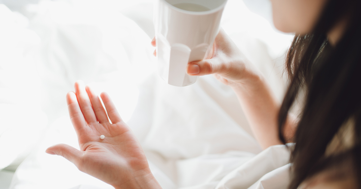 Close up of a woman holding a pill