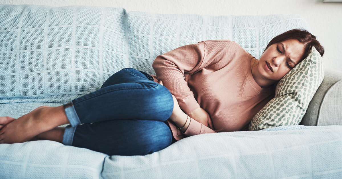 Woman lying on a couch with menstrual cramps.