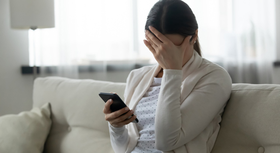 A women covering up her face while looking at her phone