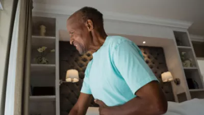 Man sitting on bed holding stomach