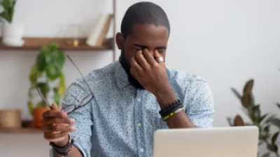 Man sitting in front of his computer rubbing his eyes