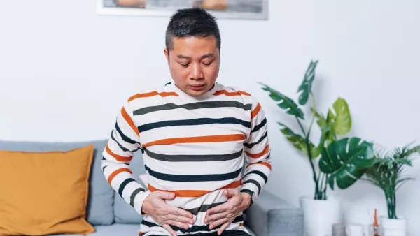 Man sitting on the couch, holding his stomach