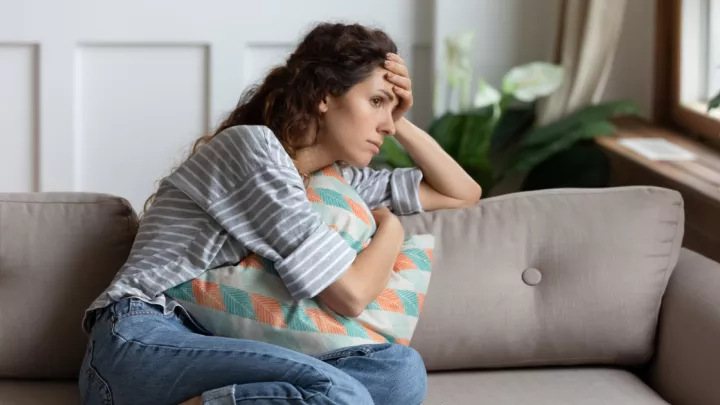 Young woman sitting on the couch looking out the window