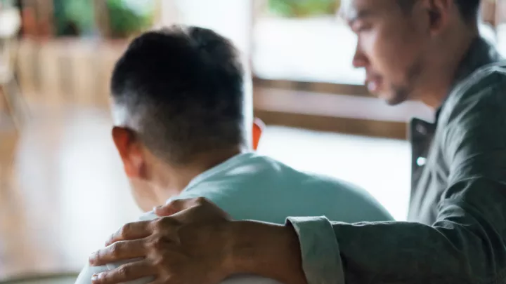 Man with his arm around an older man
