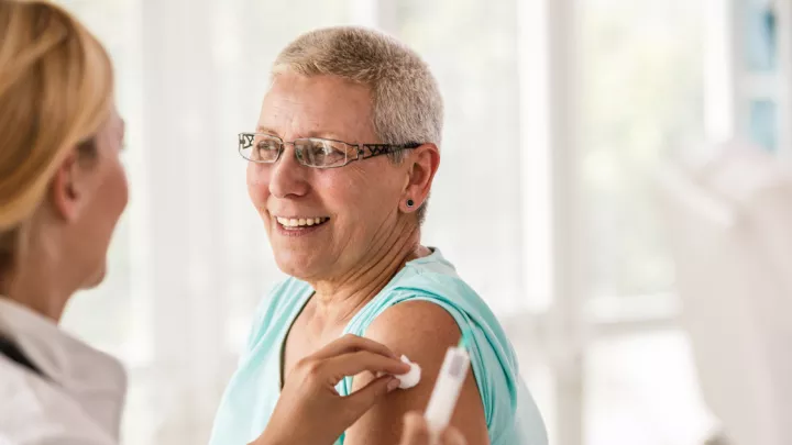 Doctor sanitizing a woman's arm before a vaccination