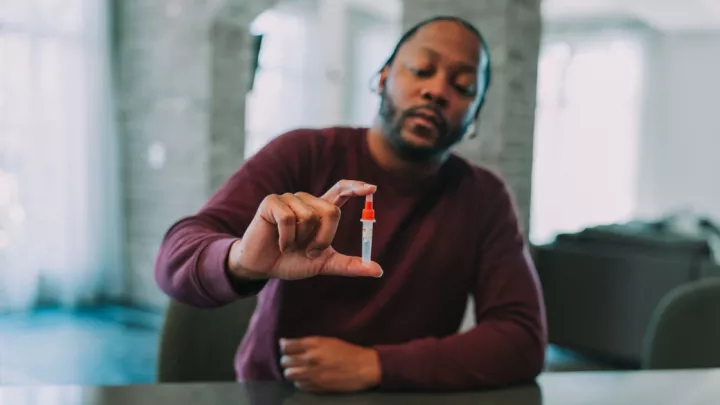 Man holding up a vial from an at-home COVID test