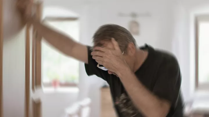Man dizzy leaning on a doorway
