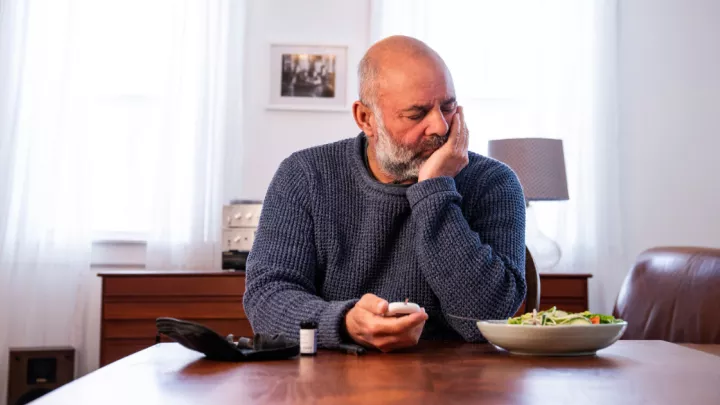 Man sitting at table holding glucose meter