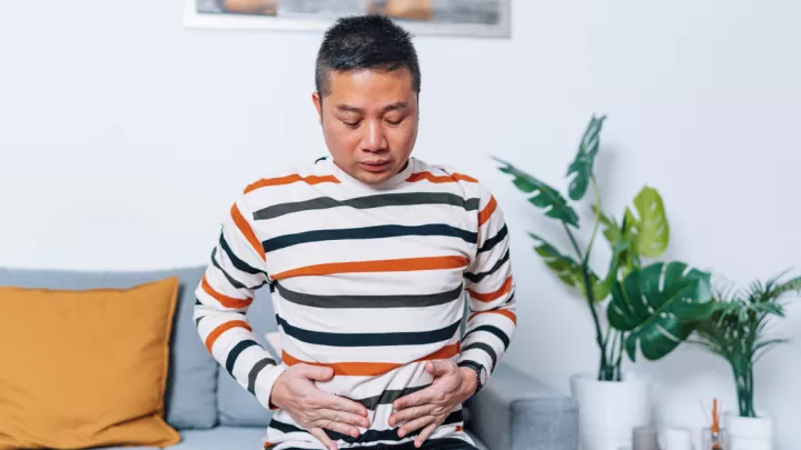 Man sitting on the couch, holding his stomach