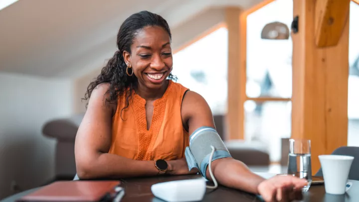 Woman sitting at a table checking her blood pressure