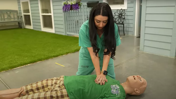 Woman performing chest compressions on a CPR dummy