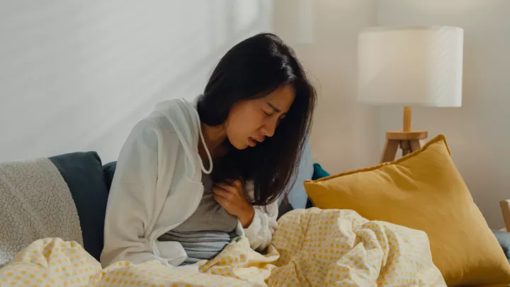 Woman sitting on the couch coughing