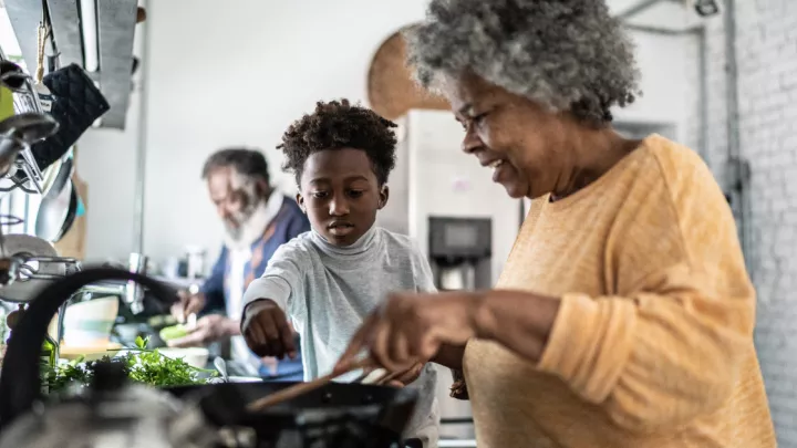 A grandmother cooking in the kitchen with her grandson