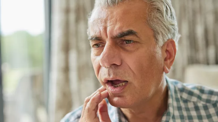Older man holding his mouth