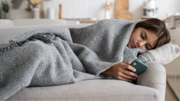 Teenage girl laying on the couch wrapped in a blanket