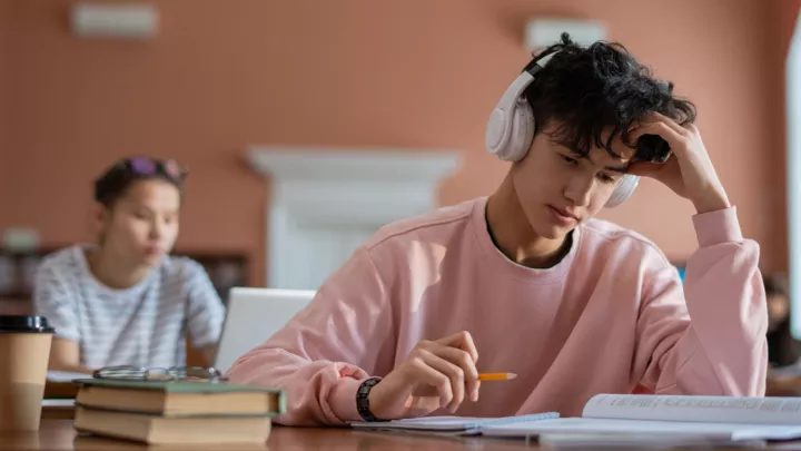 Teenage boy with headphones on, sitting in class